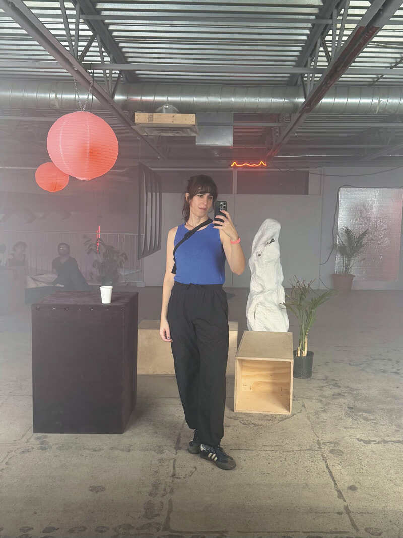 Mirror selfie. I'm wearing a blue sleeveless top and baggy black pants. My hair is pinned back in a pony tail.